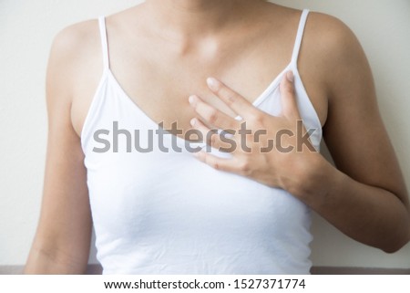 A young woman holds her hands on his chest with his eyes closed. On a gray background.
