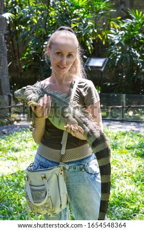 The young woman holds iguana on hands