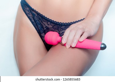 
young woman holds pink sex toy near her panties