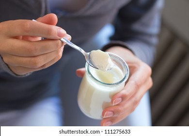 Young Woman At Home Eating Yogurt