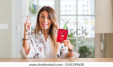Young woman at home holding a passport of Japan surprised with an idea or question pointing finger with happy face, number one
