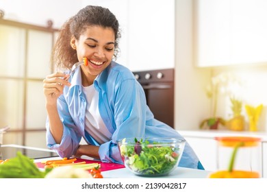 Young Woman In The Home Kitchen Eating A Genuine Salad With Fresh Vegetables