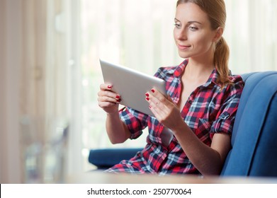 Young Woman At Home Relaxing In Her Living Room Reading A Digital Tablet PC Surf Internet And Work