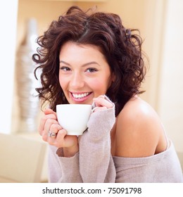 Young Woman At Home Sipping Tea From A Cup