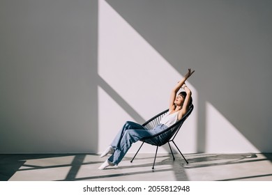 Young Woman At Home Sitting On Modern Chair Relaxing In Her Living Room