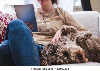 Young Woman At Home With A Tablet And A Dog