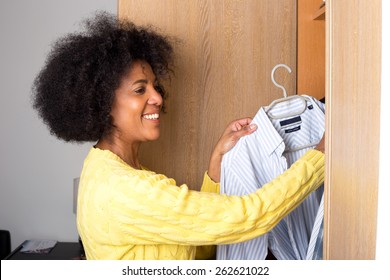 a young woman at home taking a shirt out of a wardrobe for her man. - Powered by Shutterstock