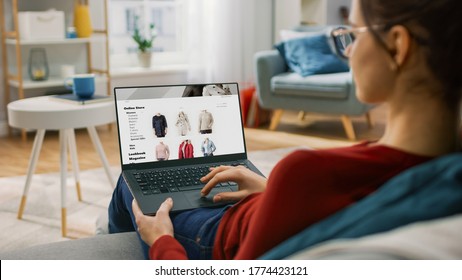 Young Woman at Home Using Laptop Computer for Browsing Through Online Retail Shopping Site. She's Sitting On a Couch in His Cozy Living Room. Over the Shoulder Camera Shot - Shutterstock ID 1774423121