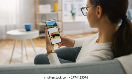 Young Woman at Home Using Smartphone, Scrolling Social Media Feed, Watching Funny Memeses. She's Sitting On a Couch in His Cozy Living Room. Over the Shoulder Camera Shot - Shutterstock ID 1774423076