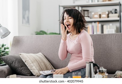 Young Woman At Home Waking Up After A Bad Night's Sleep On The Couch, She Is Yawning