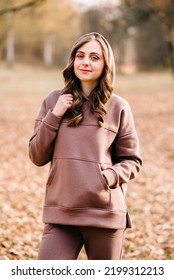 Young Woman In Hoodie In An Autumn Park. Sunny Weather. Fall Season.