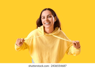 Young woman in hoodie on yellow background - Powered by Shutterstock