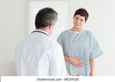 Young Woman In Hospital Gown Talking To Her Doctor In A Room