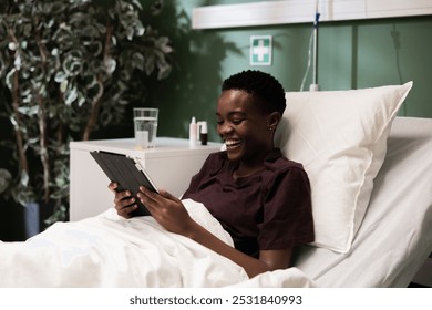 Young woman in the hospital smiles as she scrolls through pictures of adorable animals on her tablet. - Powered by Shutterstock