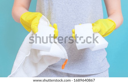 Young woman housekeeper in apron is doing cleaning with yellow gloves,white washing sponge. close up, copy space, blank design concept
