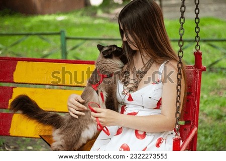 Young woman hugging an affectionate cat of Neva Masquerade breed in a park. Affectionate cat showing trust and love to its owner 