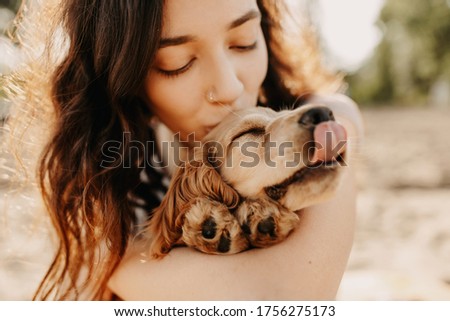 Young woman hugging and kissing her little dog, cocker spaniel breed puppy.