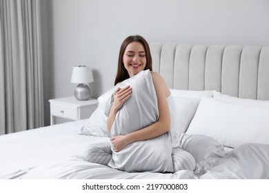 Young Woman Hugging Pillow On Comfortable Bed With Silky Linens