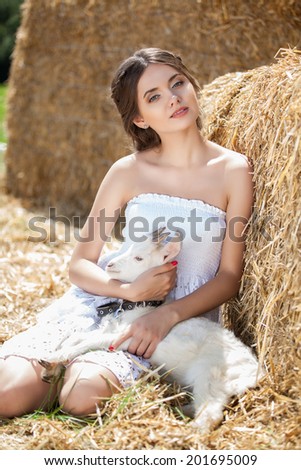 Young woman hugging a small lamb at farm