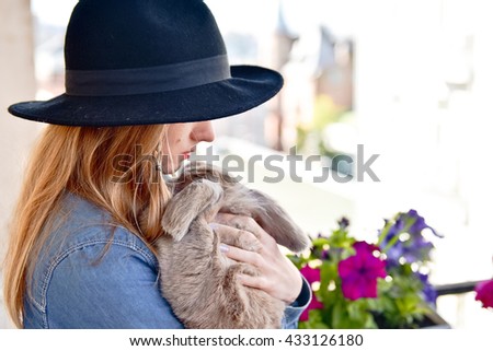 Young woman hugs big cute rabbit friend pet in her hands 