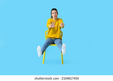 Young Woman With Imaginary Steering Wheel Sitting In Chair On Color Background