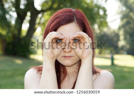 young woman imitating binoculars with her fingers around her eyes
