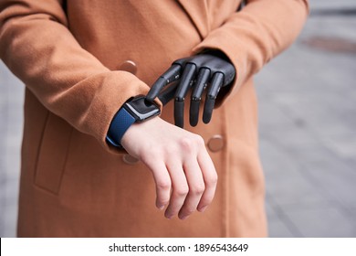 Young woman with implant arm checking time from smart watch. Young woman checking something while walking on street at autumn. Young woman looking on smartwatch her heartbeat while spending time in - Powered by Shutterstock