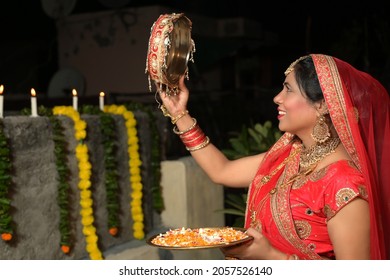 Young woman of Indian ethnicity looking through sieve on Karwa Chauth festival.