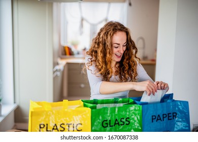 Young woman indoors at home separating glass, paper, and plastic waste. - Powered by Shutterstock