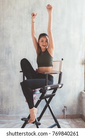 Young Woman Indoors Sitting Director's Chair Posing Looking Camera - Attitude, Blogger, Influencer Concept