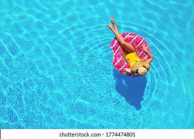 Young woman with inflatable ring in swimming pool, top view. Space for text