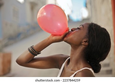 young woman inflates a balloon - Shutterstock ID 2237844259