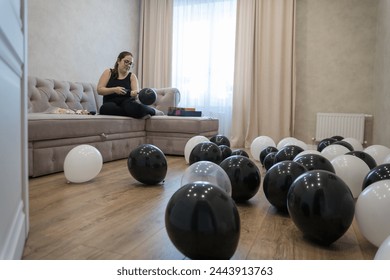 Una mujer joven infla globos con una bomba de aire manual, el concepto de inflar aire en un globo, un juego para niños, juguetes y equipos para juegos divertidos o preparación de fiestas.