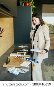 Young Woman Interior Designer Choosing Elements Of Materials For The Kitchen In A New Home Holding The Project In Hands. House Renovation Concept