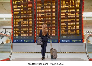 Young woman in international airport near large information display