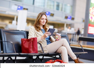 Young Woman At International Airport, Reading Her Ebook And Drinking Coffee While Waiting For Her Flight On Business Trip. Female Passenger At Terminal, Indoors.