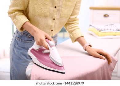 Young woman ironing clean laundry indoors, closeup. Space for text