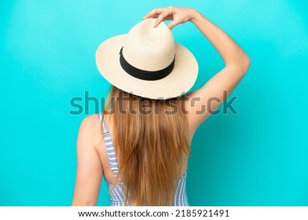 Young woman isolated on blue background in swimsuit and in back position