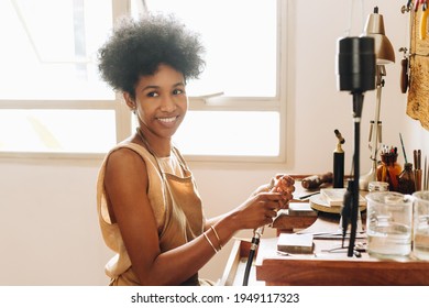 Young woman jeweler making jewelry and smiling at camera at her workshop. Cheerful African woman at her jewelry making workshop. - Powered by Shutterstock