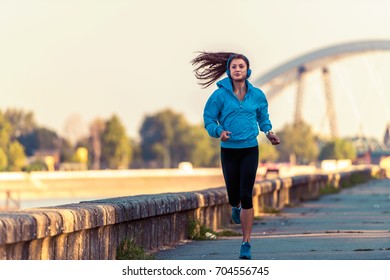 Young woman jogger  running  by the river in the morning