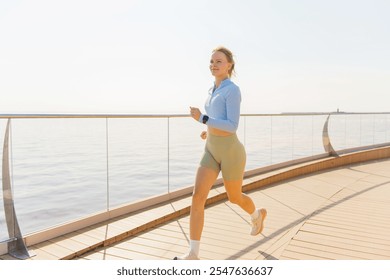 Young Woman Jogging Along a Waterfront Promenade in Bright Morning Light Near the Ocean - Powered by Shutterstock