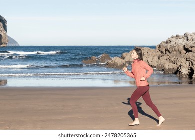 Young woman jogging barefoot on beach in pink jacket and red leggings. fitness and healthy lifestyle photography. Exercise and wellness concept - Powered by Shutterstock
