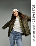 A young woman with a joyful expression showcases her trendy winter outfit with flair and confidence.