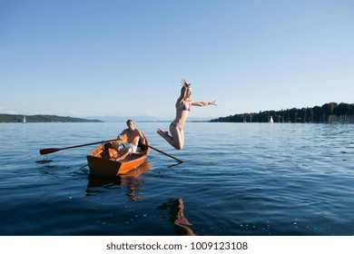Young woman jumping off a row boat