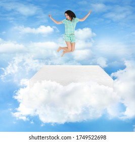 Young woman jumping on mattress in clouds