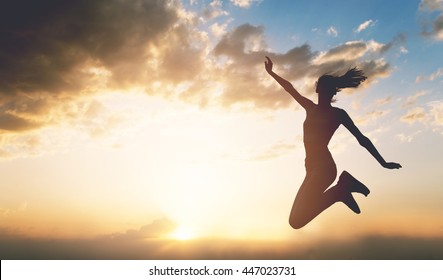 Junge Frau, die bei Sonnenuntergang nach draußen springt