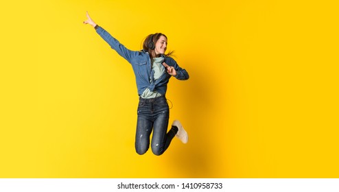 Young woman jumping over yellow background - Shutterstock ID 1410958733