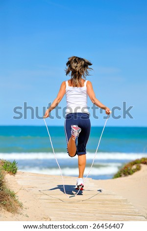 young woman with jumping rope on the beach