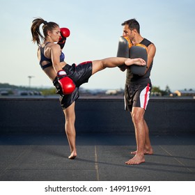 Young woman kickbox fighter training with her coach on the roof above the city - Powered by Shutterstock