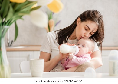 Mujer joven besa a bebé durante el consumo de leche